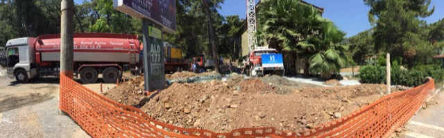 Turuncu güvenlik filesiyle çevrili sondaj sahası; solda tanker ve ortada sondaj kulesi.